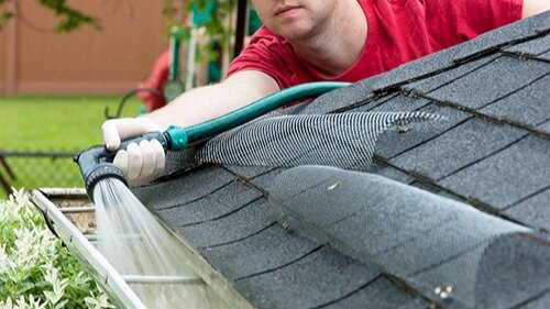 Spraying gutters out with a hose